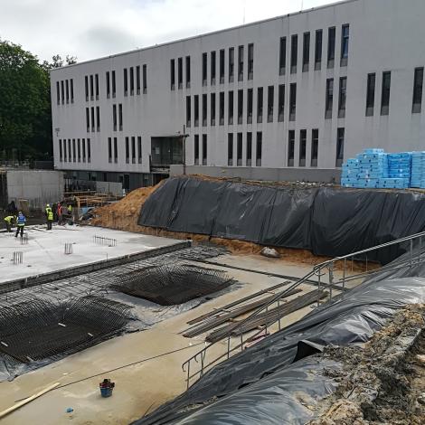 pracownicy stojący na wybetonowanych ławach, widok na zbrojenia i budynek C - Maj 2020