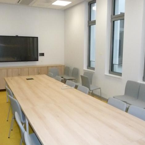 stół konferencyjny wraz z krzesłami, duży monitor na ścianie