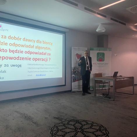 Wykładowca stojący przed ekranem ze slajdem prezentacji