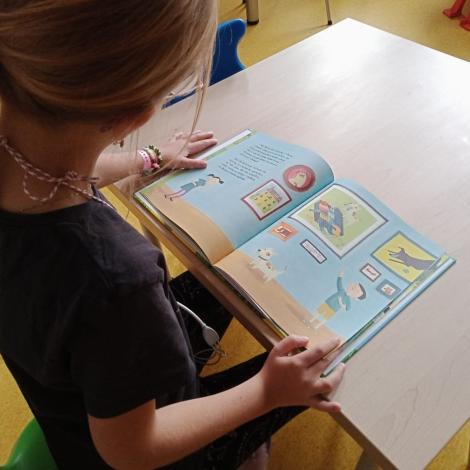 dziewczynka przy biurku przegląda książkę