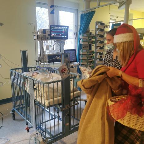 Mikołajka z workiem prezentów przy łóżeczku monitorowanym z niemowlakiem