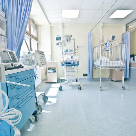 pediatryczna sala chorych z łóżeczkiem, sprzętem i pielęgniarkami za konsolą