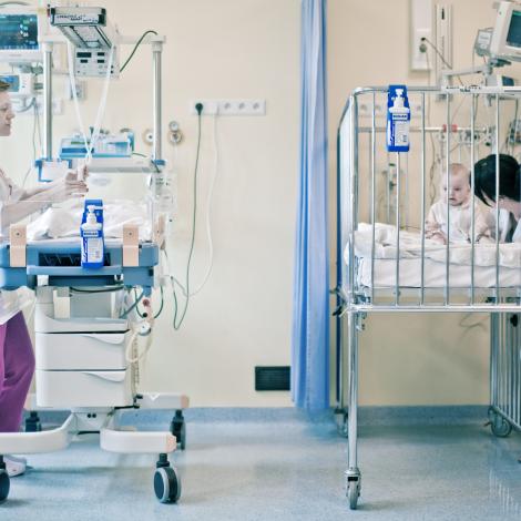 małe dziecko w łóżeczku i opiekujące się nim pielęgniarki