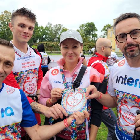 Jedna ze sztafet prezentuje złożony z czterech elementów medal biegu. 
