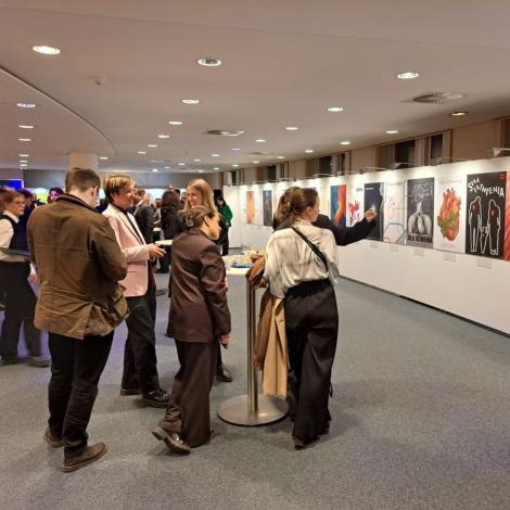 Otwarcie wystawy. Grupa młodych ludzi ogląda plakaty. 