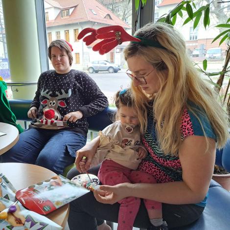 Mała pacjentka na kolanach mamy maluje witraż. 