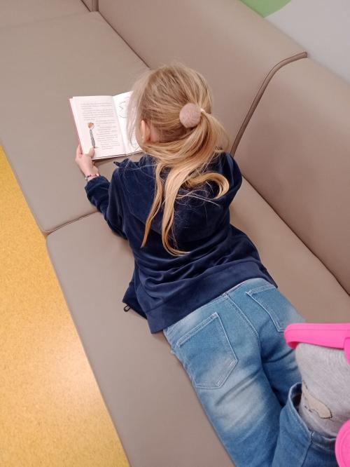 dziewczynka czytająca książkę na sofie