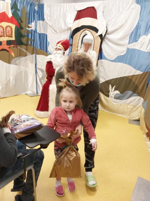 Mała pacjentka prowadzona przez mamę wracająca z prezentem na miejsce Mała pacjentka prowadzona przez mamę wracająca z prezentem na miejsce