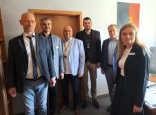 Sześć osób w strojach biznesowych pozuje do wspólnego zdjęcia w biurze.