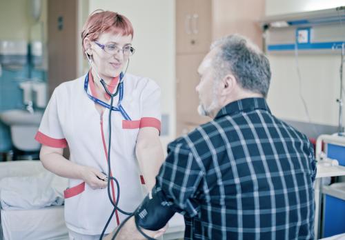 Uśmiechnięta pielęgniarka mierzy ciśnienie pacjentowi