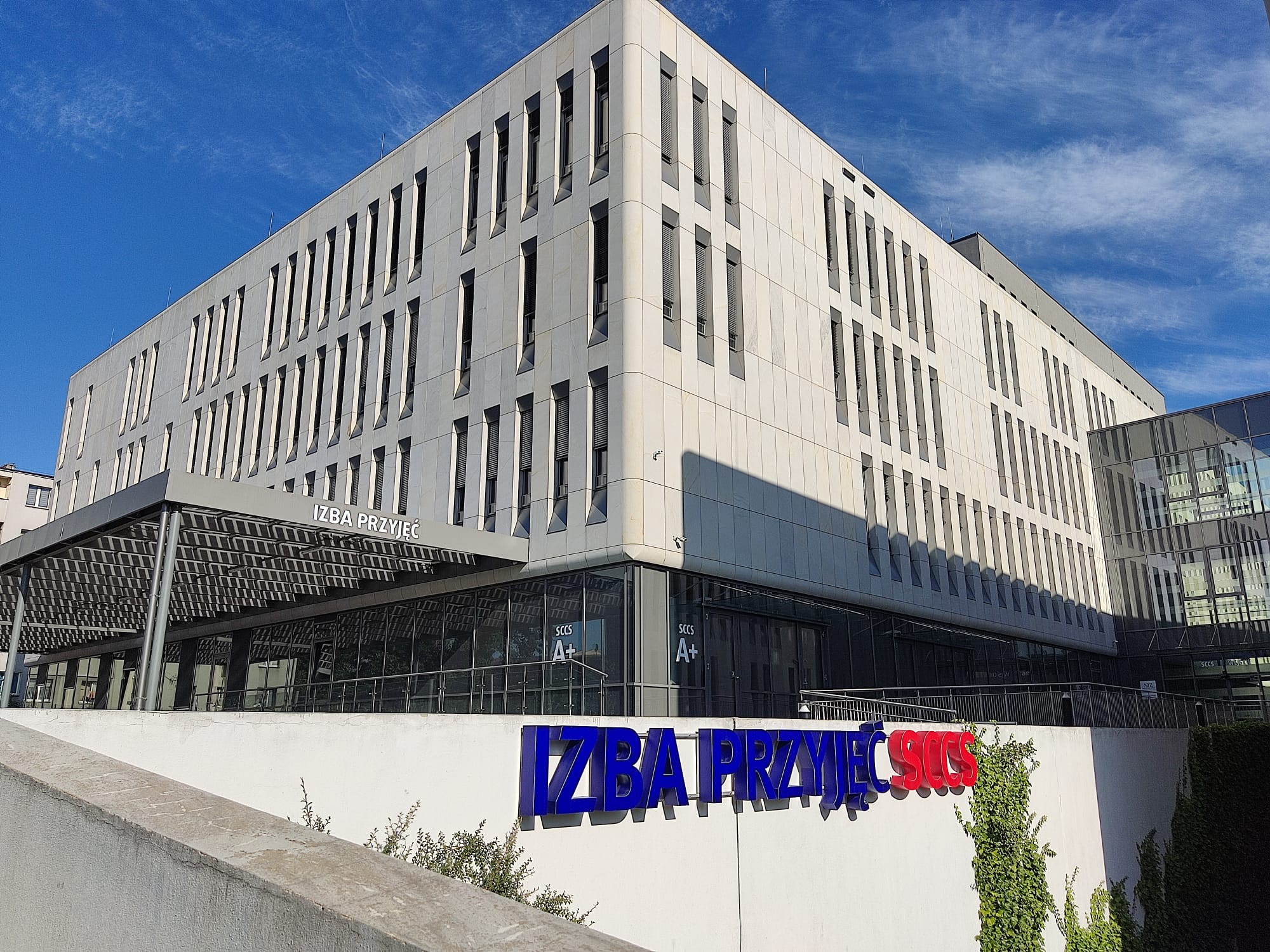 kolorowy napis na murze Izba Przyjęć, za nim budynek A+